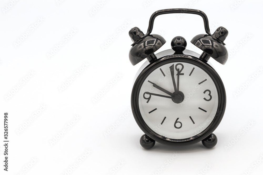 A black retro alarm clock isolated on white background. Alarm clock used to awaken people from their night's sleep or short naps. A black retro alarm clock isolated on white background. Alarm clock used to awaken people from their night's sleep or short naps.