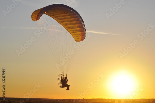 Paraglider soars in the sky. Sunset.