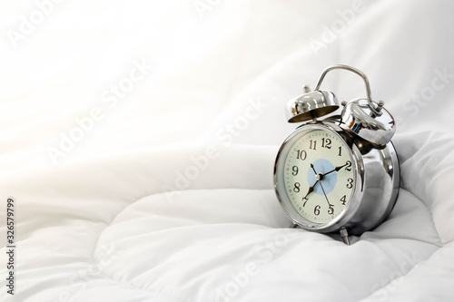 Clock alarm on bed in bedroom in the morning.