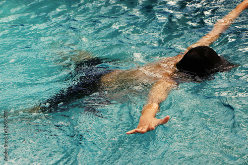 The lying down of the man swimming in the pool