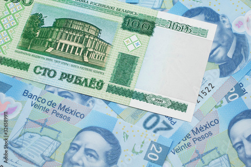An green hundred ruble bank note from Belarus on a bed of Mexican twenty peso bank notes close up in macro