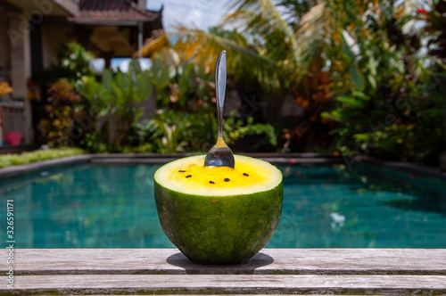 yellow watermelon with a spoon on a tropical garden background