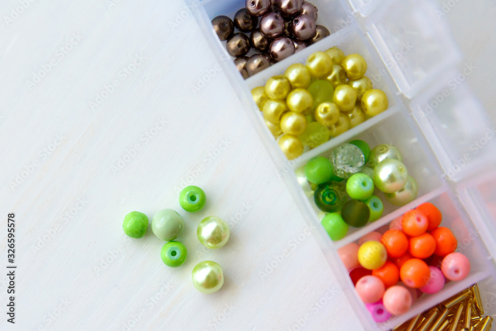 Multi-colored beads in a plastic container on the table Multi-colored beads in a plastic container on the table