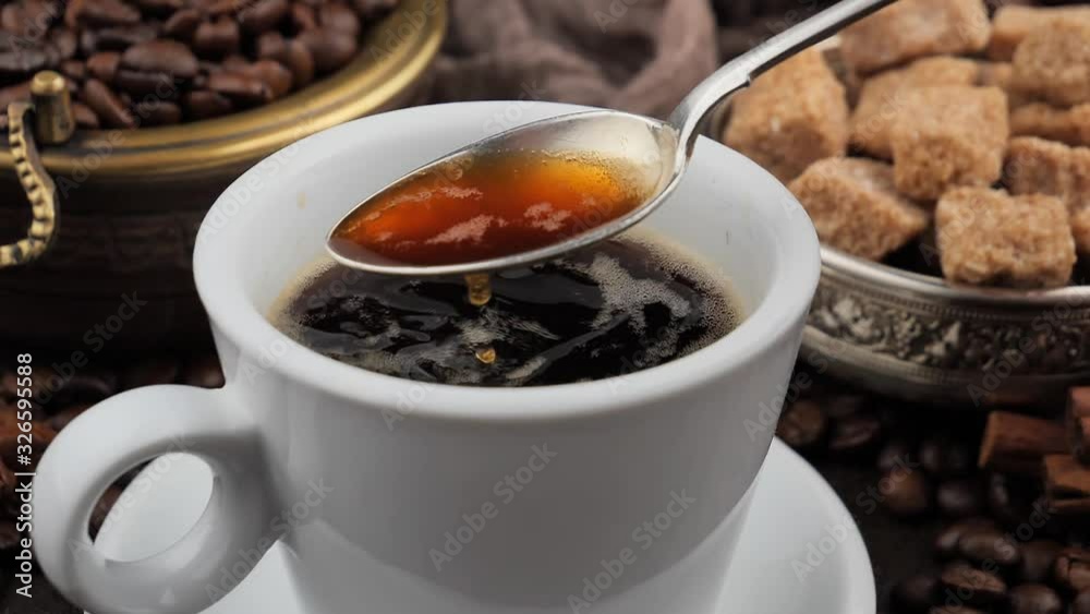 Mixing steaming coffee in a cup with a spoon Mixing steaming coffee in a cup with a spoon
