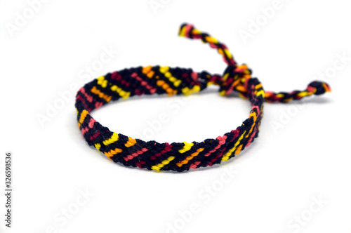 Selective focus of front side of the unisex woven friendship bracelet with ties. Handmade of multi-colored thread. Isolated on white background