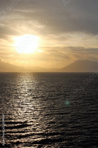 evocative image of sunset over the sea with headland silhouette in the background