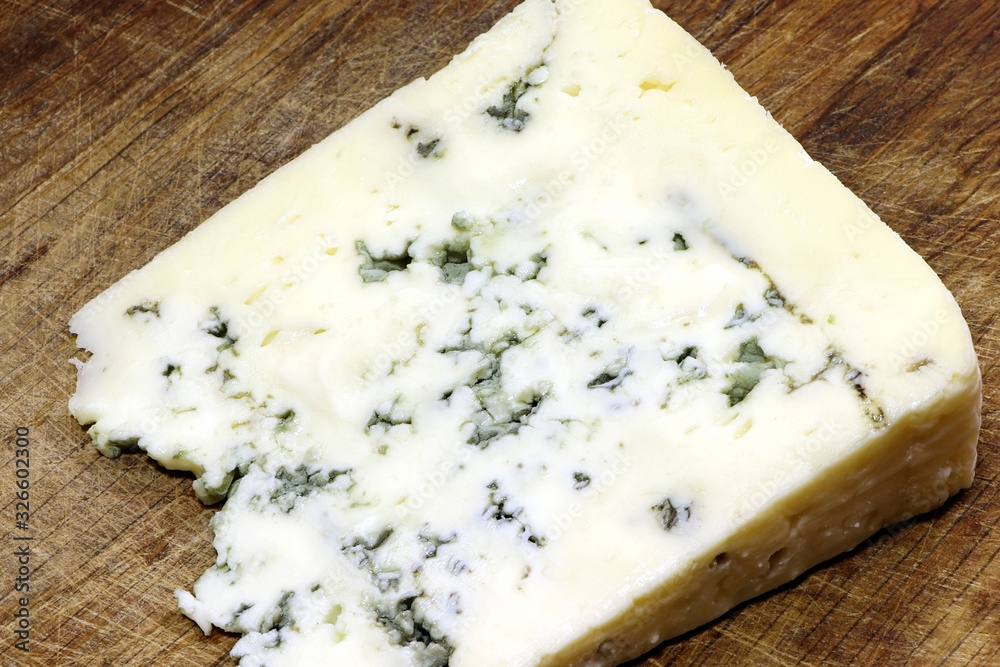 Moldy cheese on a cutting board. Blue cheese. Moldy cheese on a cutting board. Blue cheese.