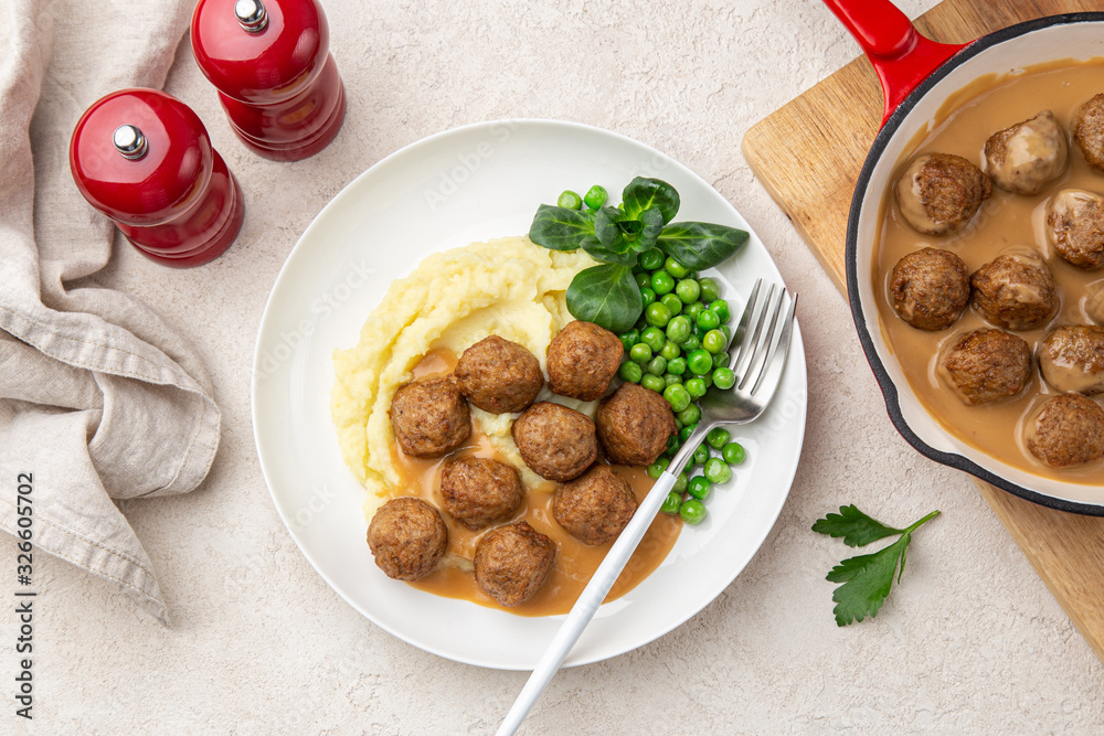 homemade meatballs with mashed potato, cream sauce and green peas on white plate