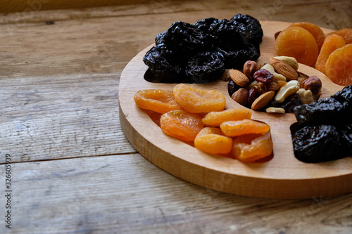 Dried apricots, prunes and nut mix at weathered wooden background