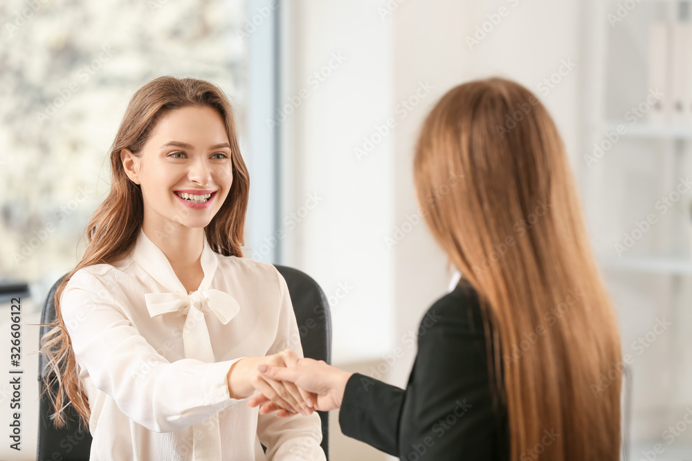 Beautiful young businesswomen shaking hands in office Beautiful young businesswomen shaking hands in office