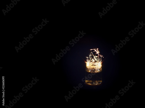 Sparkler and glass jars on a black background