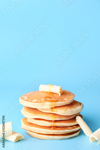 Tasty pancakes with honey and butter on color background