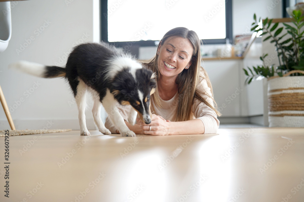 Obraz premium Woman at home sittign on floor with puppy dog