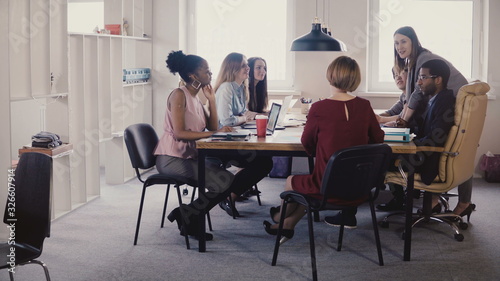 Happy female boss leading office meeting. Multiethnic employees listening to manager instructions in modern coworking 4K