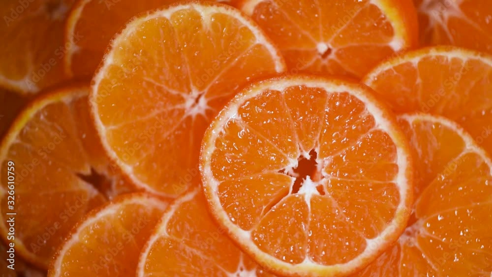 Fresh sliced orange fruit texture on rotating background. Top view. Citrus fruits. Vegan and raw food concept. Juicy oranges background