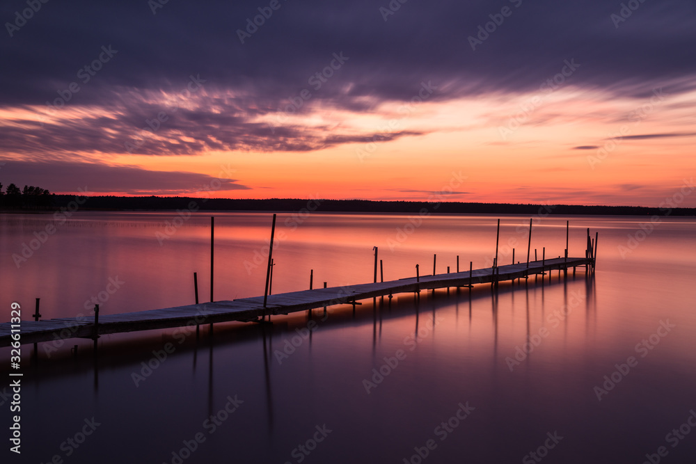 Dramatic sky over a idyllic lake with a long wooden jetty, Sweden.