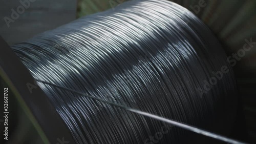 Aluminum wire is wound on the large coil in the manufacture of electric cable at the factory.