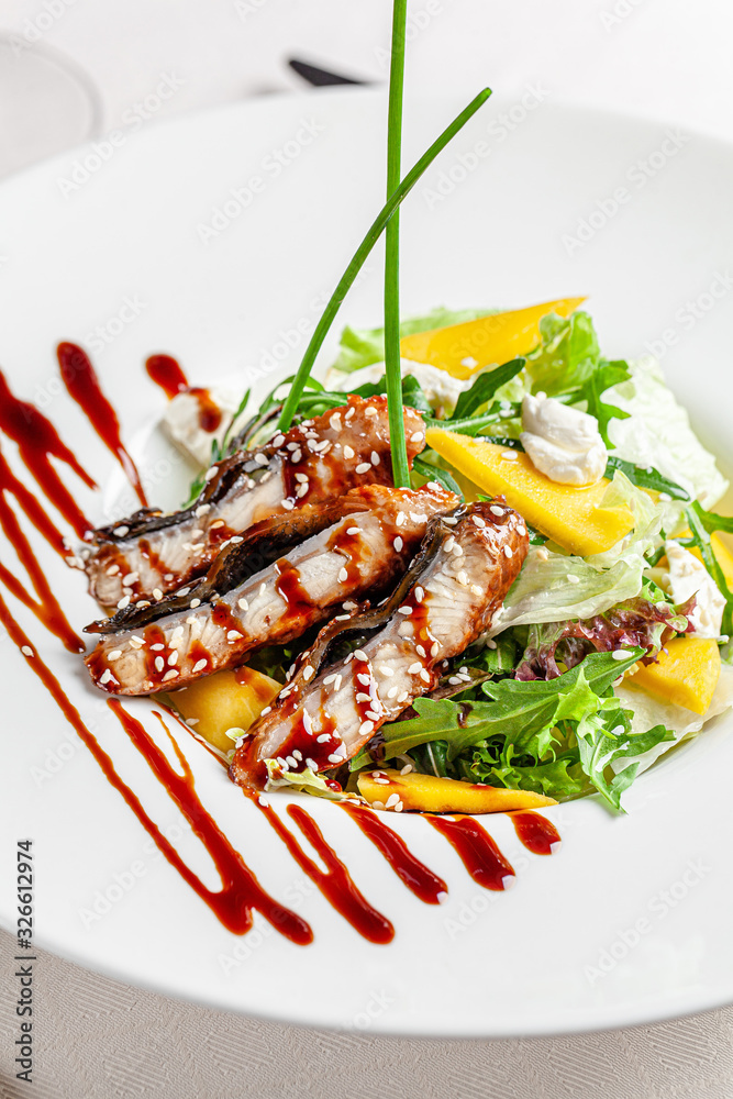 Asian cuisine in European style. Salad of sea eel, vegetables, seasoned with baslmachic vinegar and sesame seeds. Serving dishes in a restaurant on a white plate. Asian cuisine in European style. Salad of sea eel, vegetables, seasoned with baslmachic vinegar and sesame seeds. Serving dishes in a restaurant on a white plate.