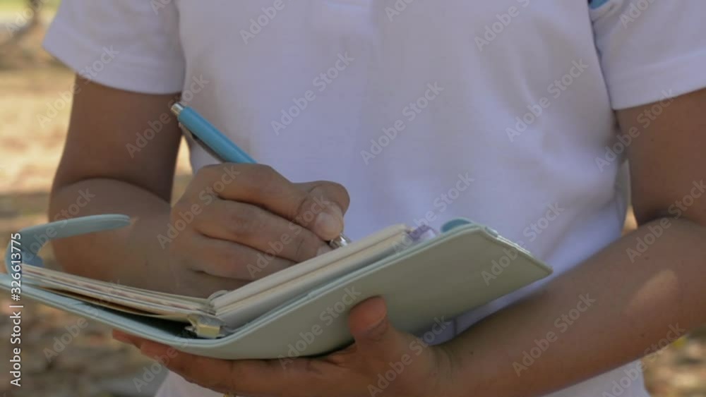 Woman walking and writing to inspire life on diary in public park during summer. Outdoor work recording. Slow motion. Woman walking and writing to inspire life on diary in public park during summer. Outdoor work recording. Slow motion.