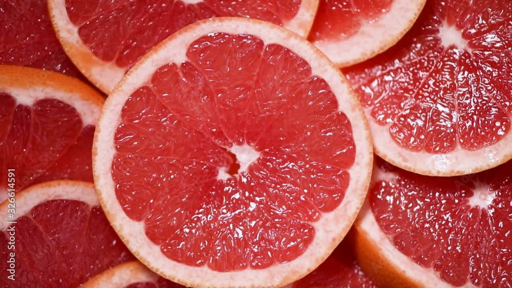 Grapefruit sliced half on rotating background. Citrus fruits. Vegan and raw food concept. Red grapefruits texture. Top view Grapefruit sliced half on rotating background. Citrus fruits. Vegan and raw food concept. Red grapefruits texture. Top view