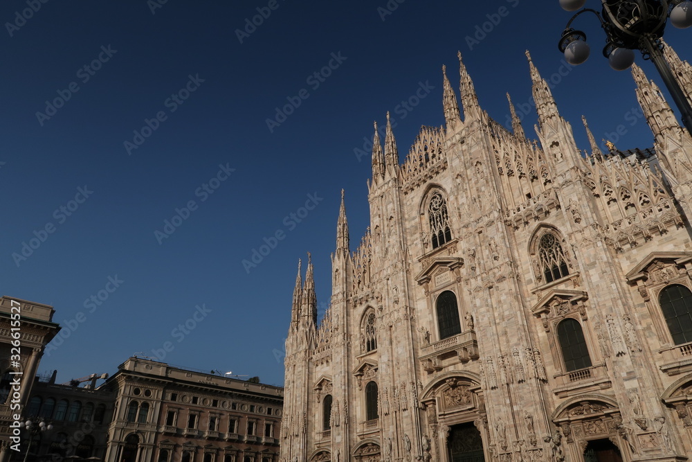 Gothic facade of Milan cathedral in white marble with spiers.