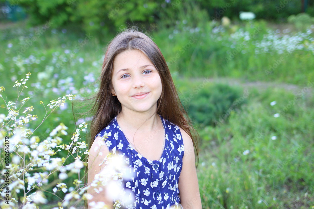 young beautiful girl in blue romper in floral print in the summer garden. Holidays and entertainment young beautiful girl in blue romper in floral print in the summer garden. Holidays and entertainment