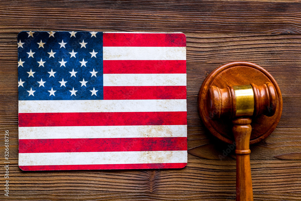 Law and justice in USA concept. Judge gavel near american flag on dark wooden background top-down