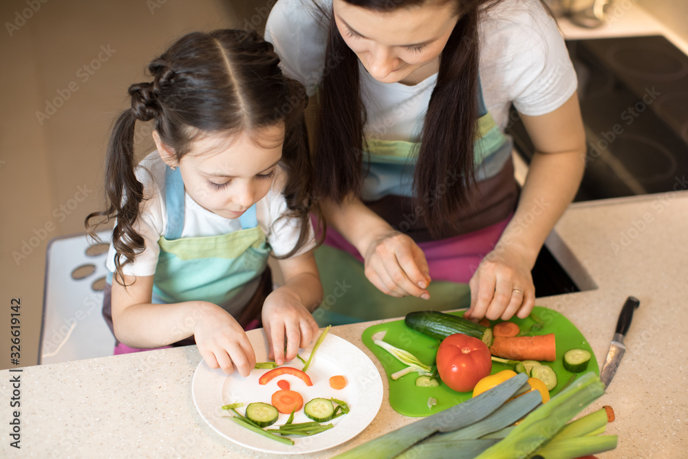 Pretty mother and her child making vegetable salad
