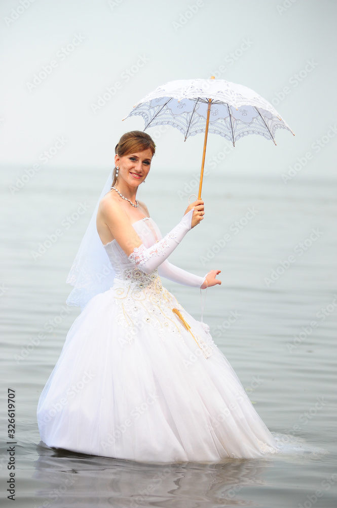 bride with a wedding umbrella in the water bride with a wedding umbrella in the water