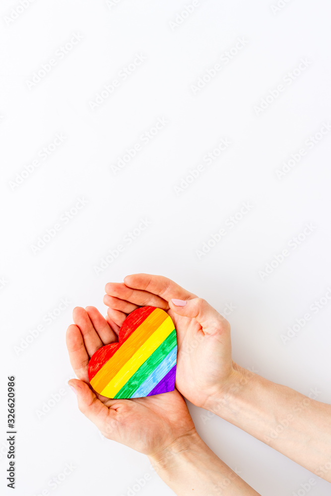 LGBT symbol. Rainbow heart in hands on white background top-down copy space