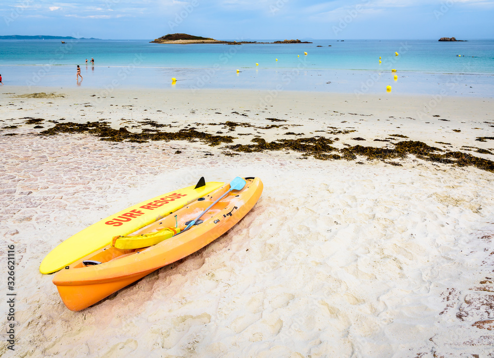Lifeguards yellow rescue surfboard and sea kayak lying on a sandy beach at low tide in Penvenan, northern Brittany, France. Lifeguards yellow rescue surfboard and sea kayak lying on a sandy beach at low tide in Penvenan, northern Brittany, France.