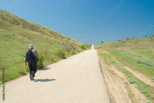 Lonely hiker walking on an empty asphalt road at spring season, Crimean peninsula