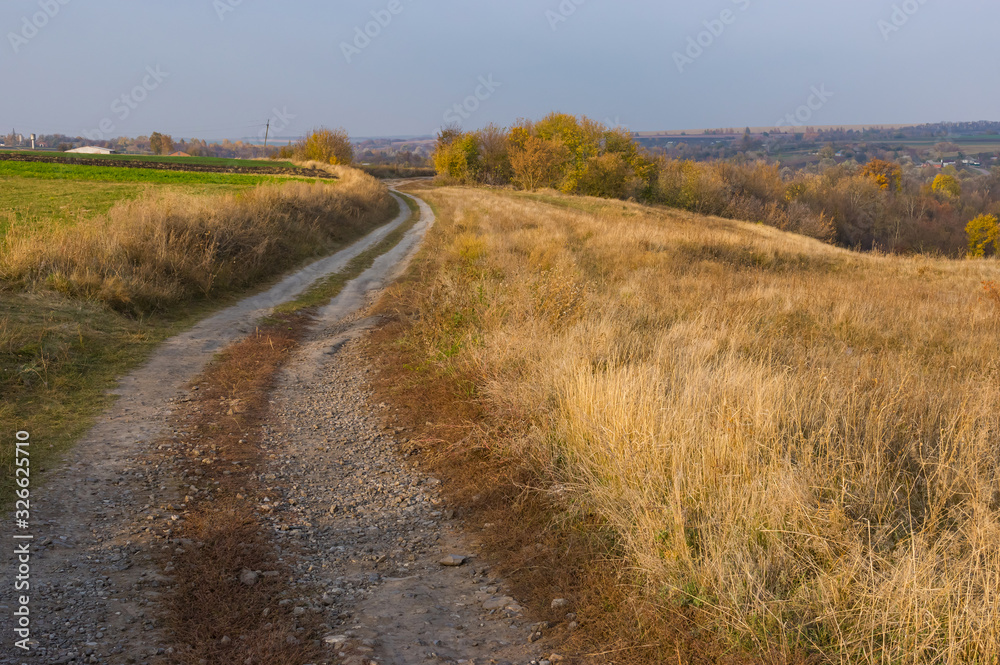 Autumnal rural landscape with earth road leading to remote village Grusheve in Sumskaya oblast, Ukraine Autumnal rural landscape with earth road leading to remote village Grusheve in Sumskaya oblast, Ukraine