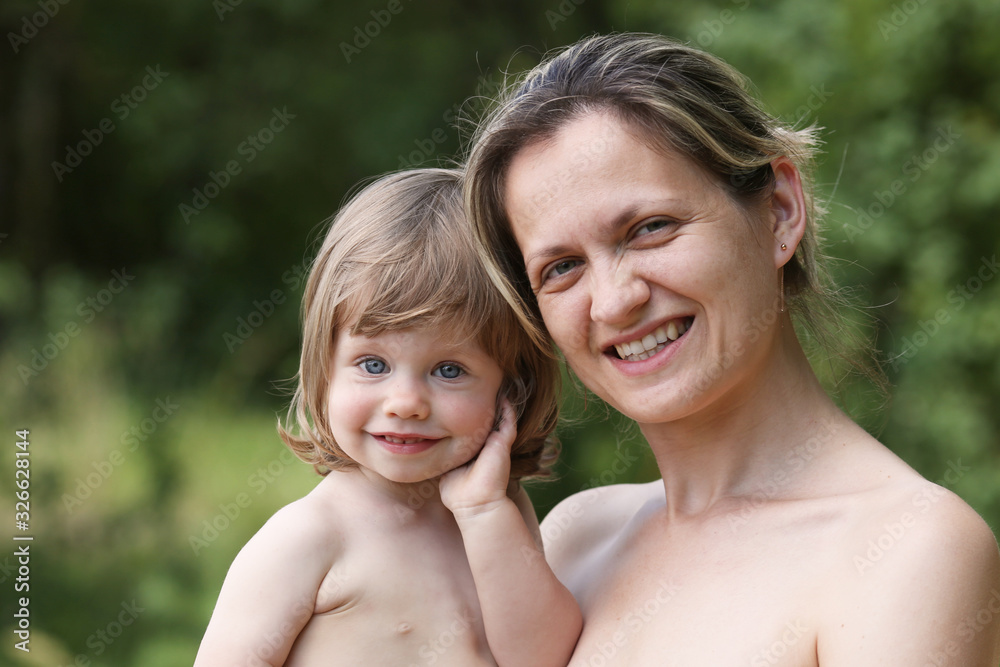 Happy little smiling child in the arms of the mother on a natural background Happy little smiling child in the arms of the mother on a natural background