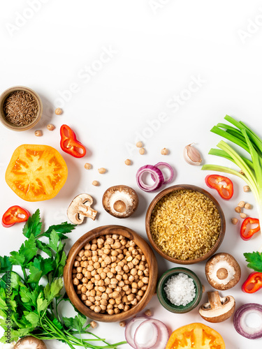 Bulgur, chickpeas, tomatoes, mushrooms, peppers, onions, spices and herbs on a white background, top view. Vegetarian and vegan food, Mediterranean cuisine ingredients. Food background, copy space