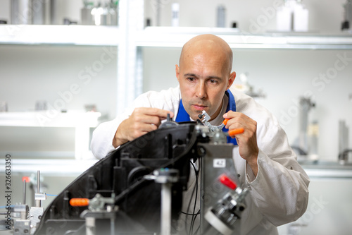 Quality engineer measuring plastic components by digital meter on the fixture, automotive and metrology concept