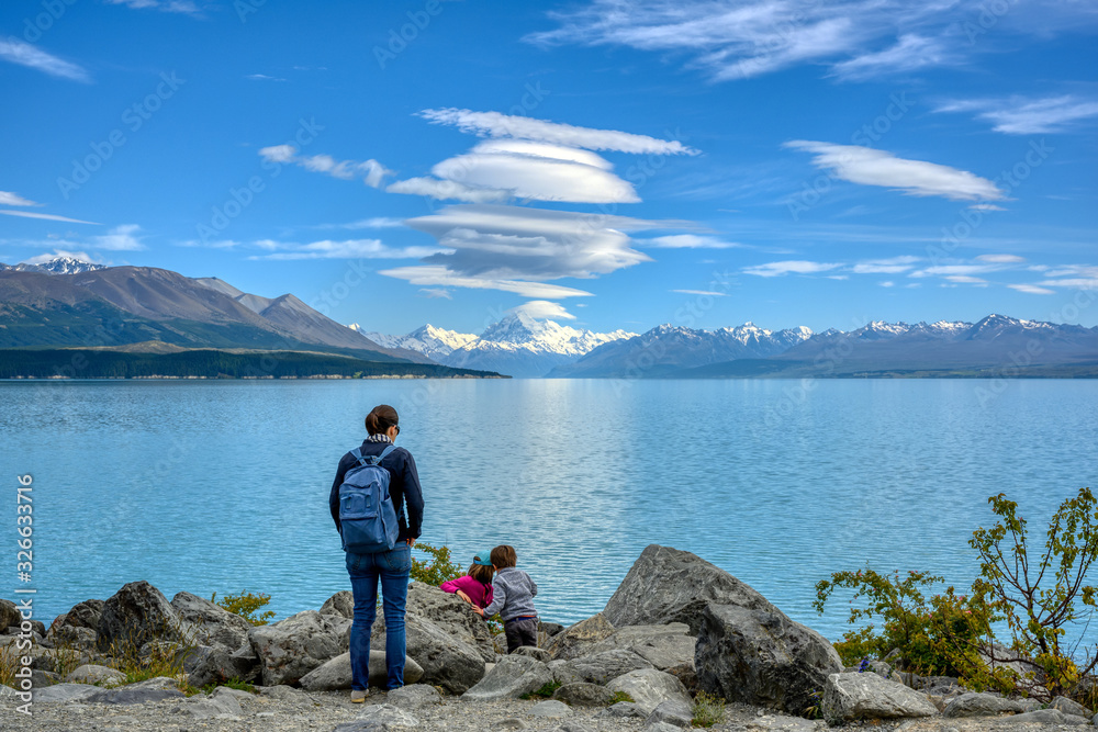 Family tourists Mother is looking at two children enjoying the beautiful and great nature at Pukaki Lake. During the daytime in Pukaki, Canterbury, New Zealand. Family tourists Mother is looking at two children enjoying the beautiful and great nature at Pukaki Lake. During the daytime in Pukaki, Canterbury, New Zealand.