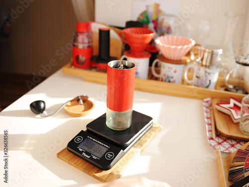Alternative brewing still life. Red manual coffee grinder on electronic scale. Third wave specialty aesthetics concept