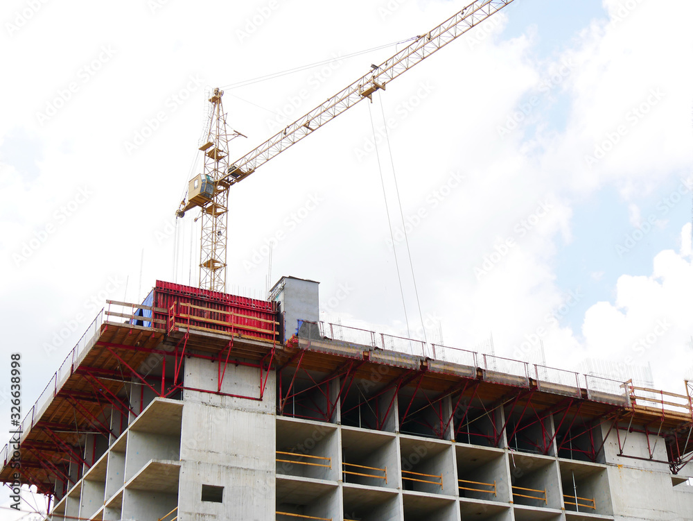 Work on the construction site. Hoisting cranes and building activity. Construction site with cranes on sky background.