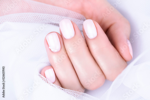 Nude Nail Polish. Beige manicure with pearls on a white background. 