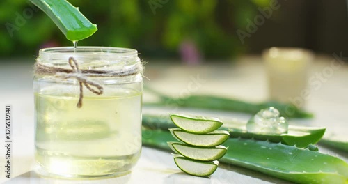 Closeup green fresh organic aloe vera leaf with aloevera slices in wooden spoon isolated on white background. Top view. Flat lay.