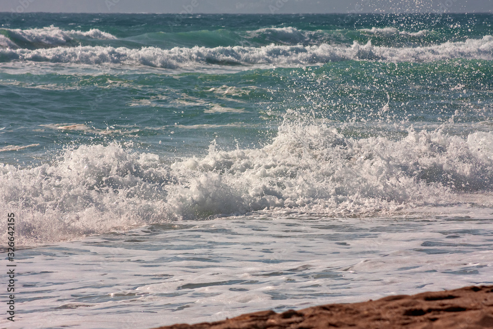 Fototapeta premium The foaming waves of the rough sea break on the beach.
