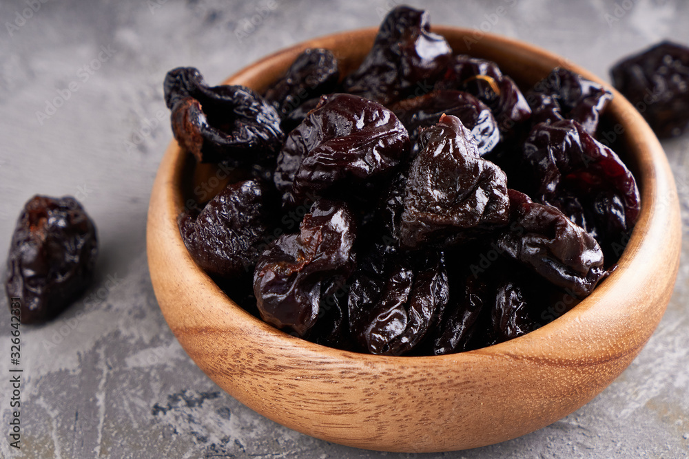 prunes, dried plums in a wooden bowl on a gray background Rustic style prunes, dried plums in a wooden bowl on a gray background Rustic style