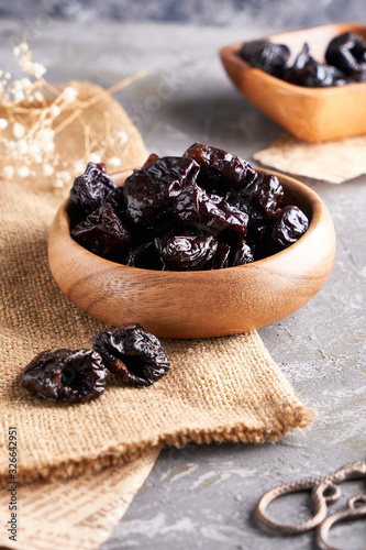 prunes, dried plums in a wooden bowl on a gray background Rustic style