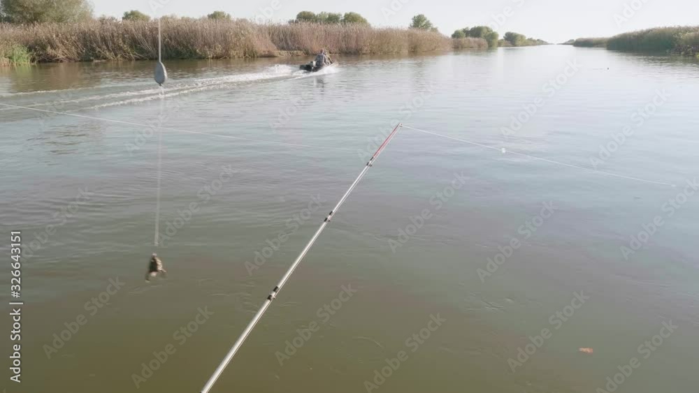 Frog as bait on hook. Two fishermen on boat pass by on river. Frog as bait on hook. Two fishermen on boat pass by on river.
