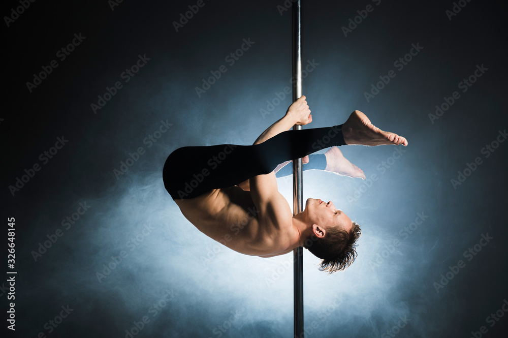 Fototapeta premium Professional young male performing a pole dance