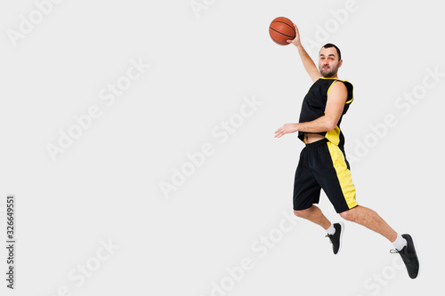 Side view of man posing mid-air while dunking with copy space © FreepikCompany