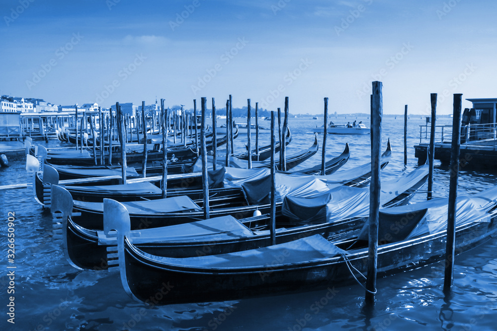 Gondolas moored in front of Saint Mark square in Venice, Italy. Classic Blue Pantone 2020 year color.