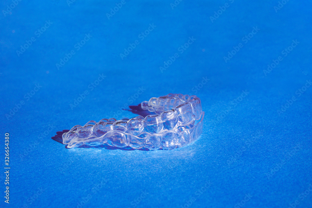 Invisible aligners teeth brackets on blue background Invisible aligners teeth brackets on blue background