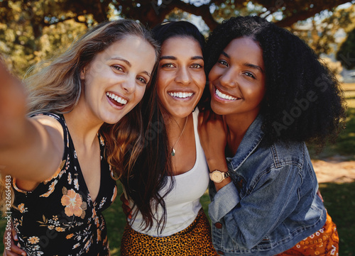 Fototapeta Close-up self portrait of smiling young multiethnic female friends taking selfie